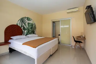 a bedroom with a bed and a chair and a tv at Cove Kanaya in Denpasar