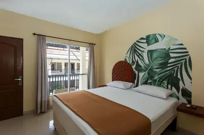 a bedroom with a bed and a large window at Cove Kanaya in Denpasar