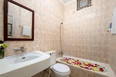 a bathroom with a sink and a toilet and a tub at Lumbung Sari Hotel Legian in Legian