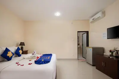 a bedroom with a large white bed with blue pillows at Lumbung Sari Hotel Legian in Legian