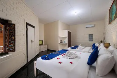 a bedroom with two beds and a couch at Lumbung Sari Hotel Legian in Legian
