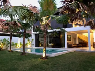 a house with a swimming pool and palm trees at Villa Denira in Nusa Dua