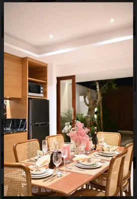a dining room table with chairs and a table with wine glasses at T villa in Seminyak
