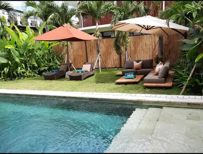 a swimming pool with chairs and umbrellas next to a pool at T villa in Seminyak