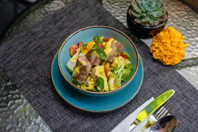 a bowl of salad with meat and vegetables on a table at Le Cielo Resort Umalas by Maviba in Canggu