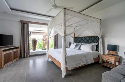 a bedroom with a canopy bed and a television at Villa Alopa 1 in Seminyak