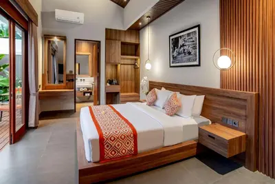 a bedroom with a large bed and a bathroom at Pondok Arya Kuta Villas by Kamara in Kuta