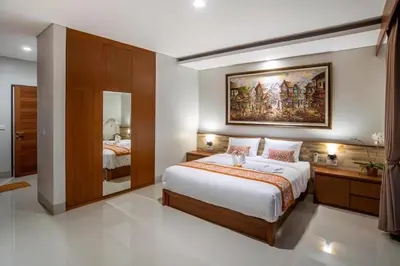 a bedroom with a large bed and a painting on the wall at Pondok Arya Kuta Villas by Kamara in Kuta