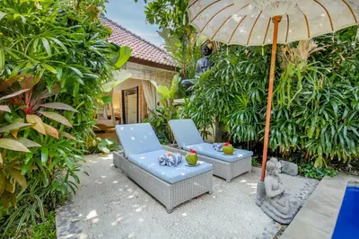 a patio with two chairs and an umbrella at Villa Balissima in Seminyak
