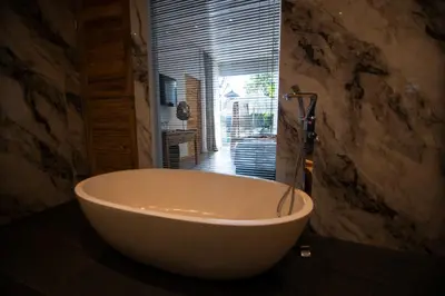 a large white bath tub in a bathroom with a window at Villa Loba in Seminyak