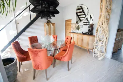 a dining room with a glass table and orange chairs at Villa Loba in Seminyak