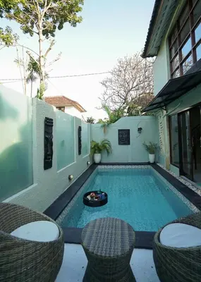 a small swimming pool with chairs and a table at Villa Indalia in Seminyak