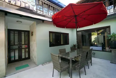 a patio with a table and a red umbrella at Villa Indalia in Seminyak