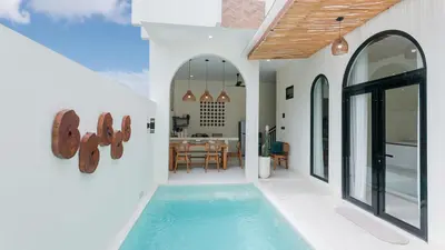 a house with a swimming pool and a dining room at Seffalas Villa by Betterplace in Canggu