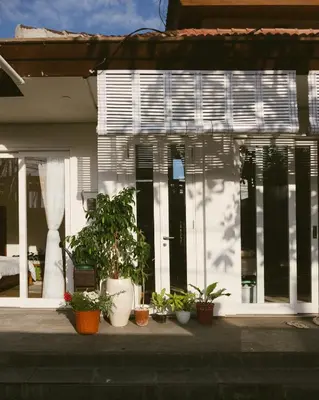 a white house with potted plants in front of it at DORALICE by a Paddy Field in Kerobokan