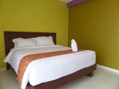 a bedroom with a large bed with white sheets at Alkyfa Hotel Bali in Denpasar
