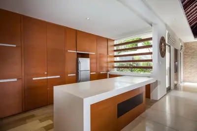 a kitchen with a white counter and wooden cabinets at Villa Illam in Seminyak