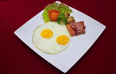 a white plate with an egg and meat and vegetables at Villa Illam in Seminyak