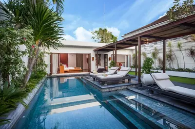 an infinity pool with lounge chairs and a house at Villa Illam in Seminyak