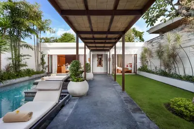 an outdoor patio with lounge chairs and a swimming pool at Villa Illam in Seminyak