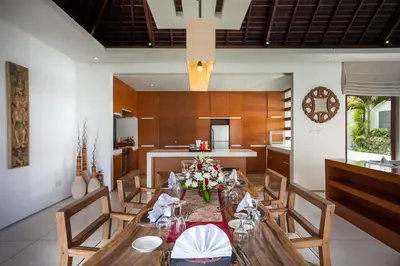 a dining room with a table and a kitchen at Villa Illam in Seminyak