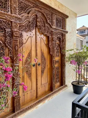 an ornate wooden door on a building with flowers at Villa Solas Legian in Legian