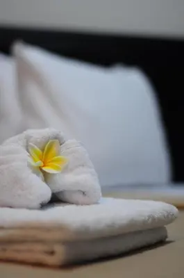 a white towel with a yellow flower on it at Amerta Home Stay Bali in Denpasar