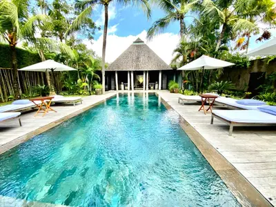 a pool at a resort with chairs and umbrellas at Villa Samuan in Seminyak