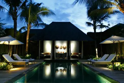 a villa with a swimming pool with chairs and umbrellas at Villa Samuan in Seminyak