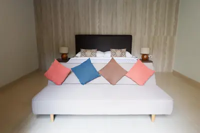 a bedroom with a white bed with colorful pillows at The BALIem Villa in Jimbaran