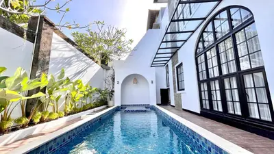 an indoor pool in a house with windows and plants at The BALIem Villa in Jimbaran