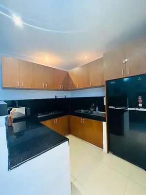 a kitchen with wooden cabinets and a black counter top at De'Huta Villa in Canggu