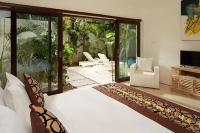 a bedroom with a bed and a sliding glass door at Yoga Villa in Seminyak
