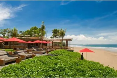 a resort with chairs and umbrellas on the beach at Yoga Villa in Seminyak