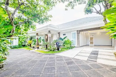 a white house with a driveway and trees at Desa Residence Kerobokan in Kerobokan