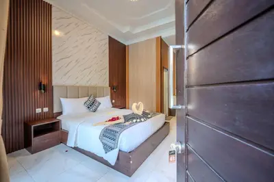 a small bedroom with a bed and a wooden door at Wana Kubu Homestay in Kuta
