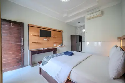 a bedroom with a bed and a tv on a wall at Wana Kubu Homestay in Kuta