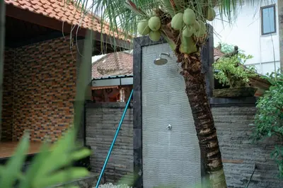 a hose hooked up to a house with a palm tree at Wana Kubu Homestay in Kuta