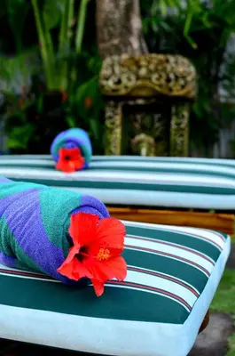 a row of beds with a red flower on them at Room & Vespa 1 - Stay Central Seminyak Near Beach in Seminyak