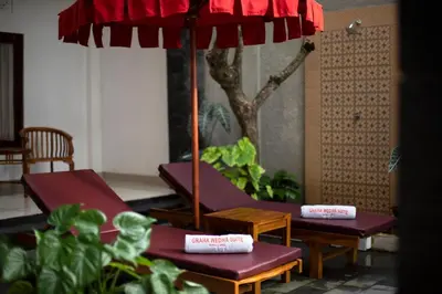 a patio with two chairs and an umbrella at Graha Wedha Suite Kuta by kamara in Kuta