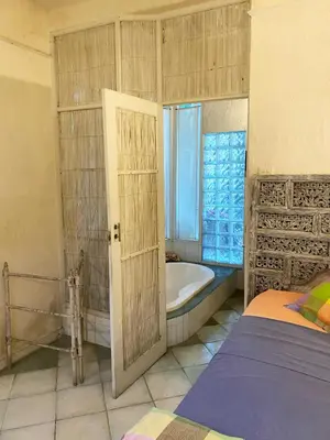 a bathroom with a tub and a bed and a window at Shady Grove Healing Centre & Homestay w house rules please read before booking in Sanur
