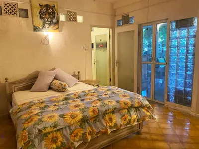 a bedroom with a bed with a floral comforter at Shady Grove Healing Centre & Homestay w house rules please read before booking in Sanur