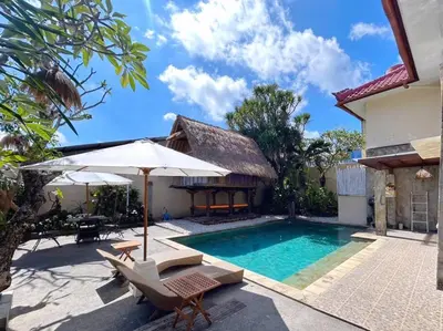 a pool with chairs and an umbrella next to a house at kuta 5BR private villa pool ,near airport, in Kuta