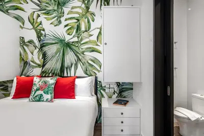 a bedroom with a white bed with red pillows and a tropical wallpaper at Villa Balik II Seminyak in Seminyak
