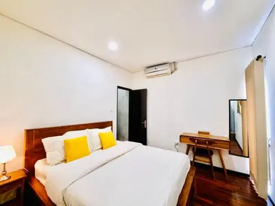 a bedroom with a bed with yellow pillows and a desk at Bali 3BR Family Nicho House in Seminyak