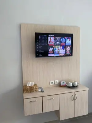 a tv on a wall above a wooden cabinet at Queen’s Villa in Seminyak