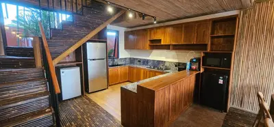 a kitchen with wooden cabinets and a staircase at Bamboo Estate Legian in Legian