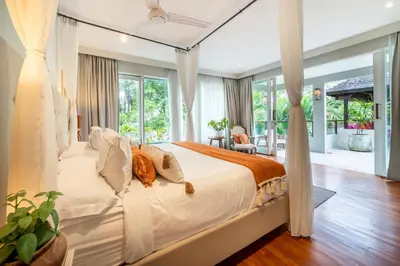 a bedroom with a bed with white sheets and curtains at Villa Sunsara 4 - Enchanting 4BR Villa in a Great Location in Canggu