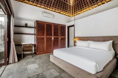 a bedroom with a large white bed and a window at Villa Iris in Dalung