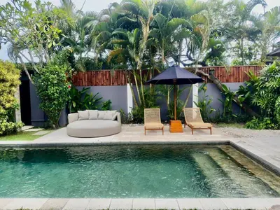 a pool with two chairs and a couch and an umbrella at Villa Iris in Dalung